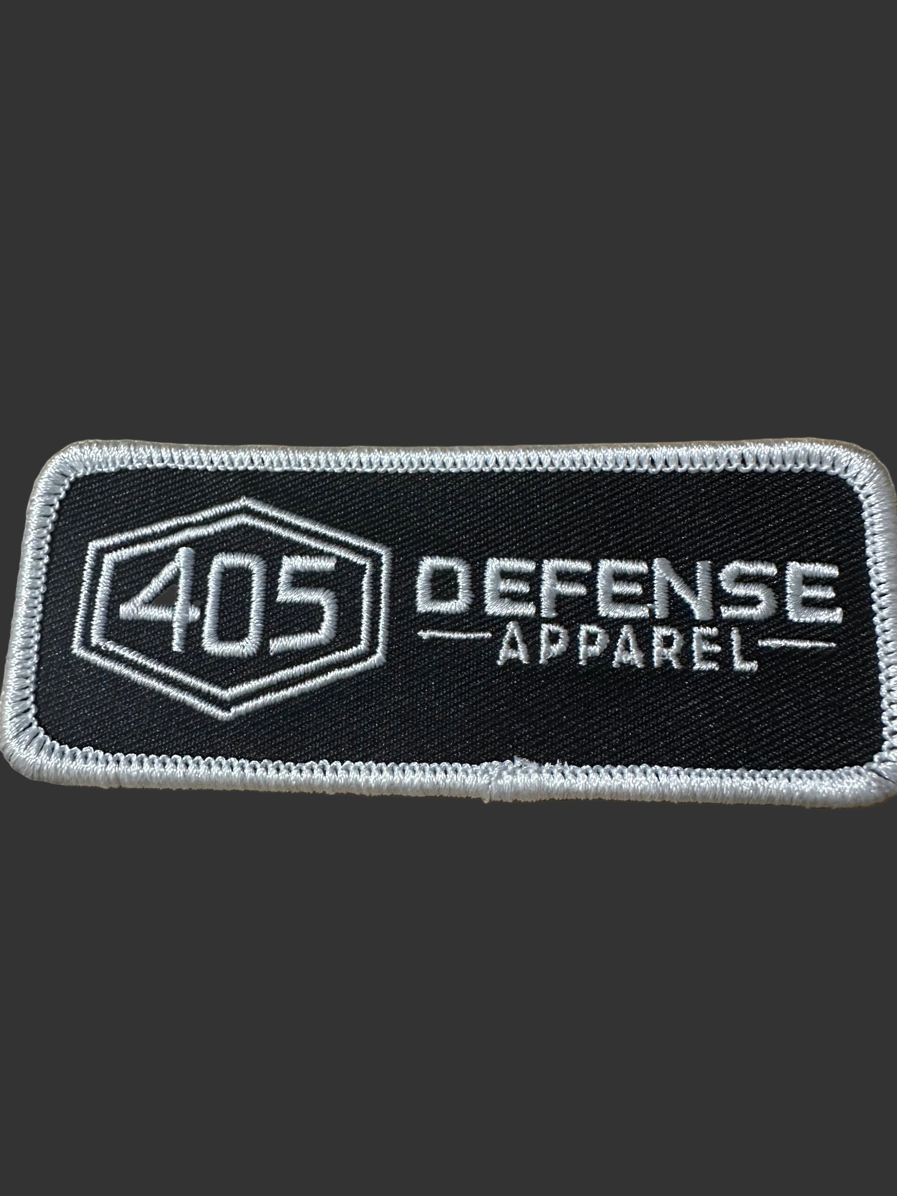 405 Defense Apparel embroidered morale patch featuring the hex logo and Defense Apparel text in white stitching on a black background with hook backing.
